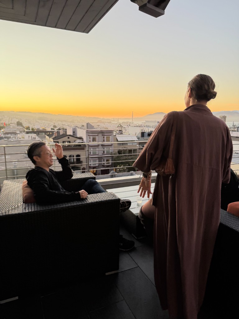 Guests on a rooftop in San Francisco at sunset during the AI meetup.